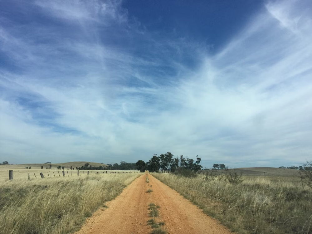 A country road beneath a wide blue Australian sky